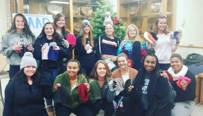 Softball team makes donations to the glove and hat drive